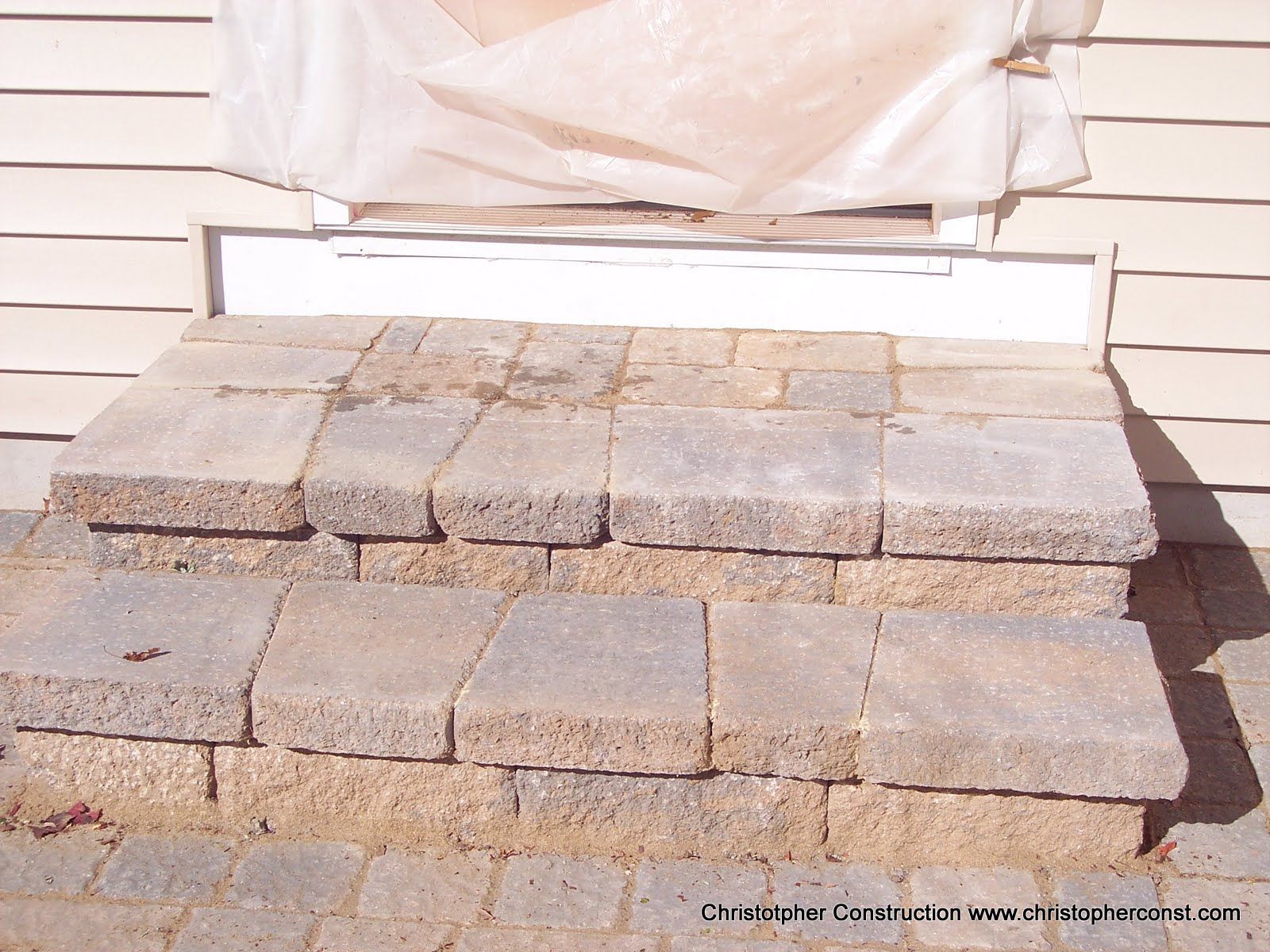 Stack of gray paving stones on a porch in front of a white house wall