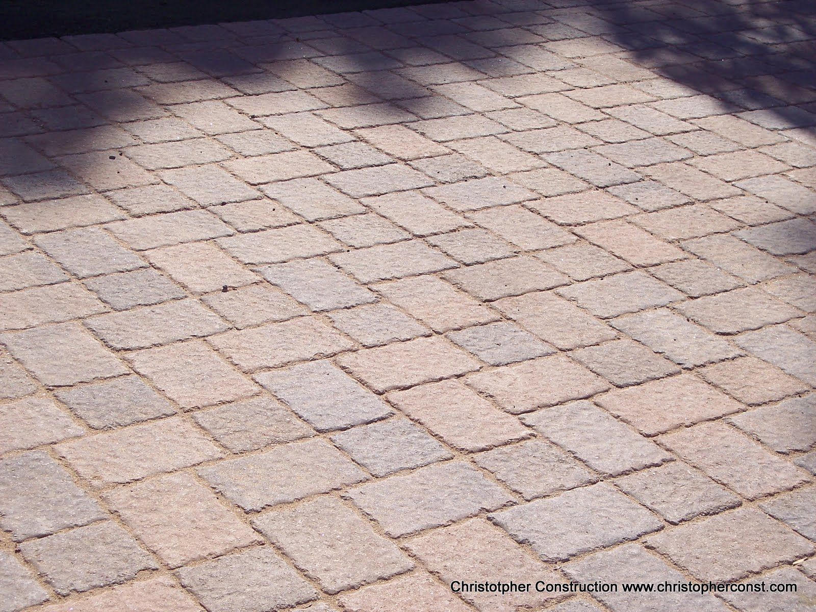 Stone-paved ground with diagonal square tiles in soft pink and gray tones.