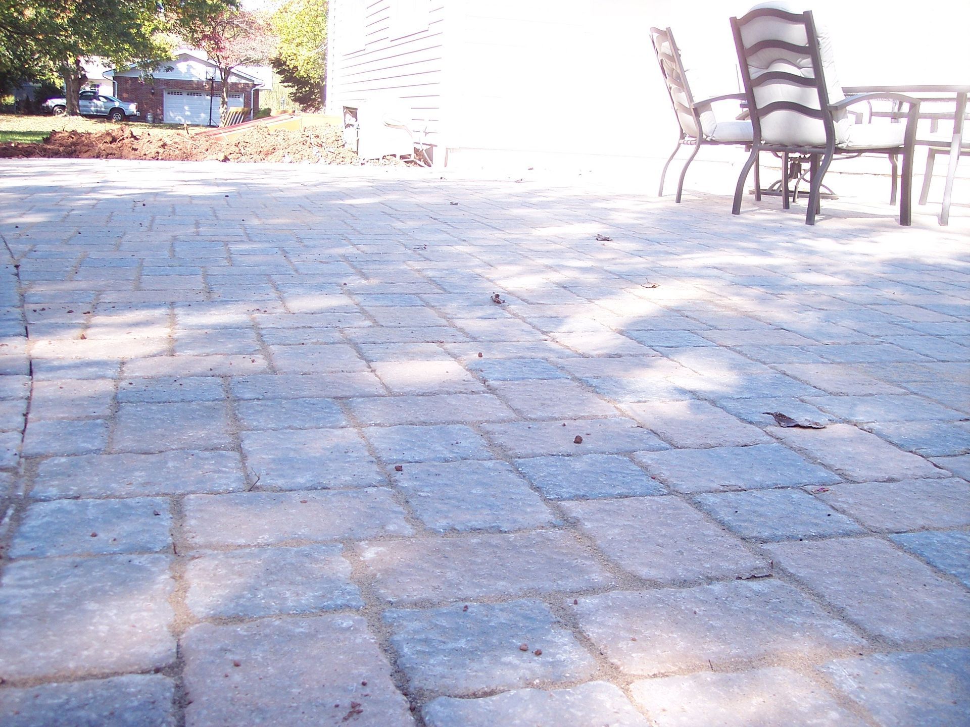 Sunny stone patio with outdoor chairs and table beside a building