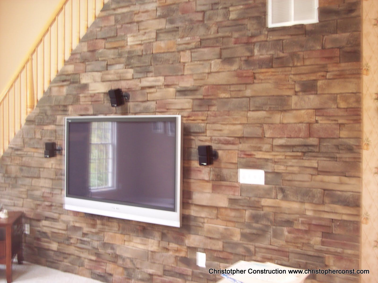 Stone exterior wall with a large window and mounted lights beside a staircase