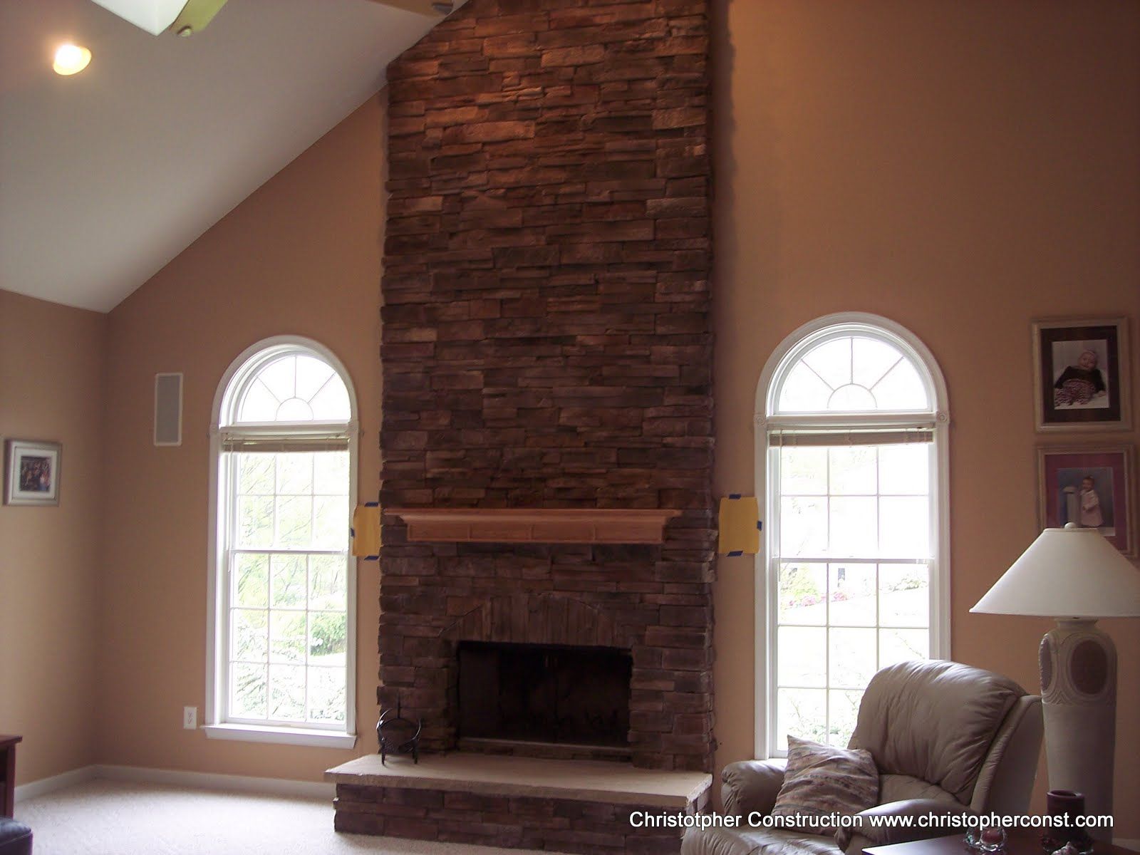 Living room with stone fireplace, arched windows, and beige walls