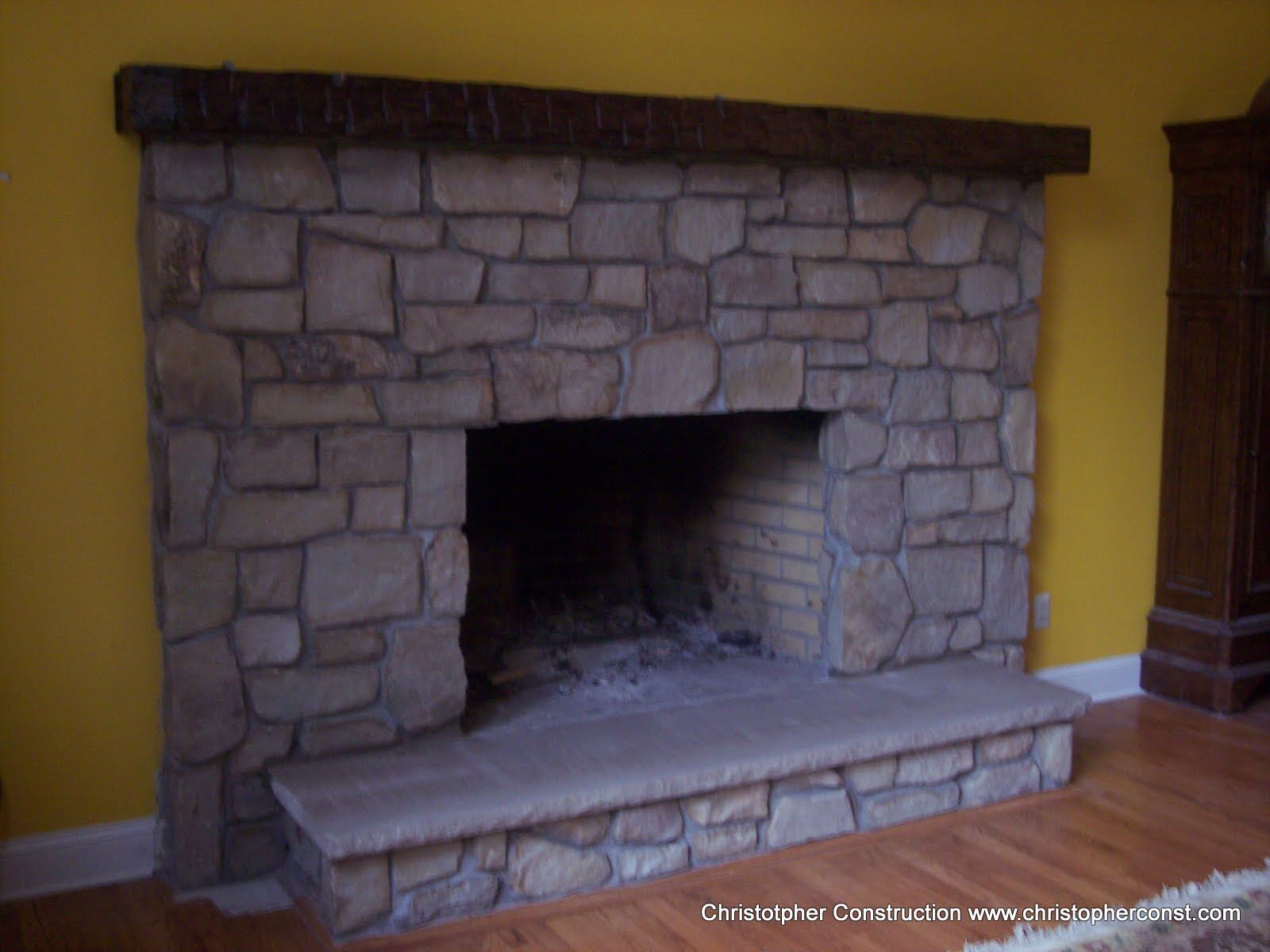 Stone fireplace with a wooden mantel in a yellow room