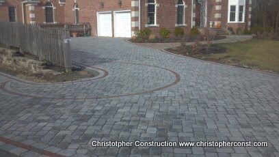 Curved gray stone driveway leading to a brick house with a white garage door