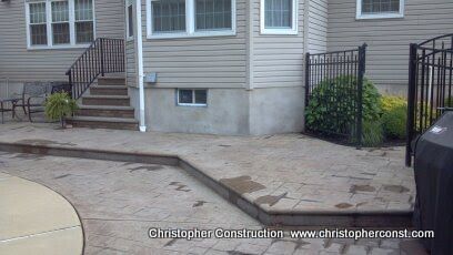 Front entrance with wheelchair-accessible ramp and paved walkway beside a beige building