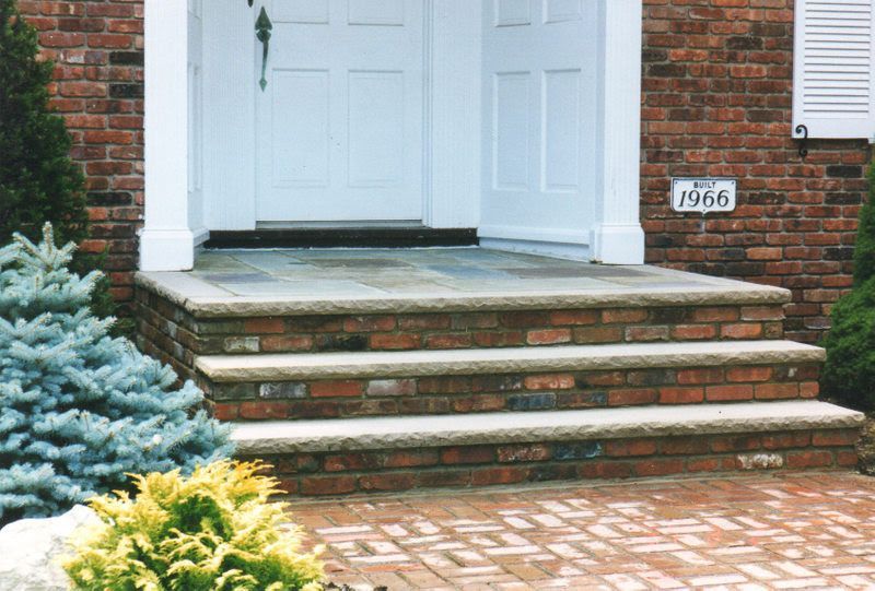 Brick house front steps leading to white double doors, with a small 1966 plaque by the entrance