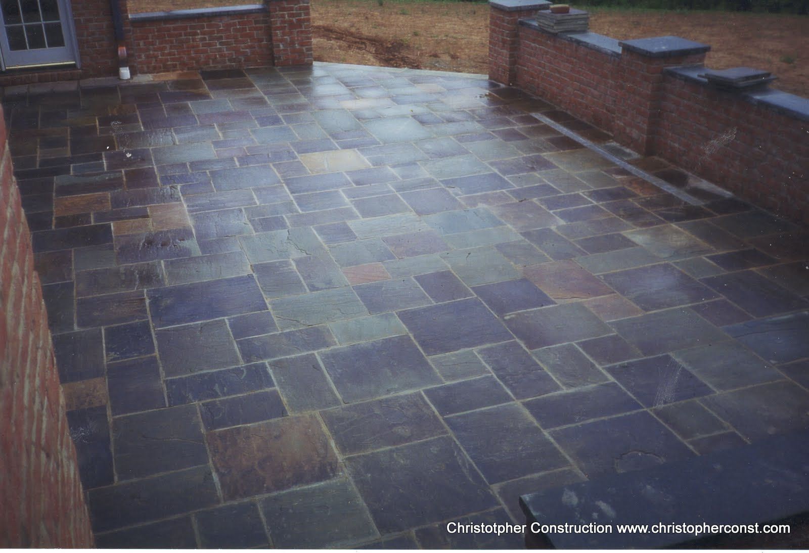 Wet stone-tiled patio with brick walls and a garden view