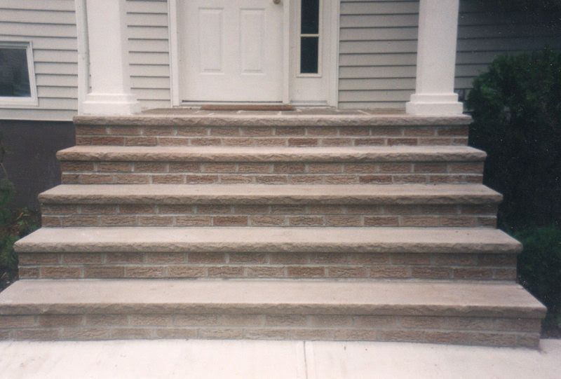 Front steps of a white house with wide stone stairs and columns at the entrance
