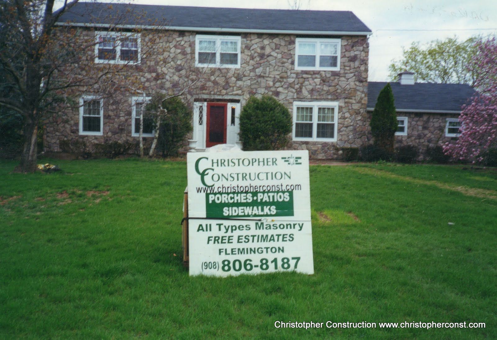 Brick house with a lawn sign advertising Christopher Construction home improvement services.