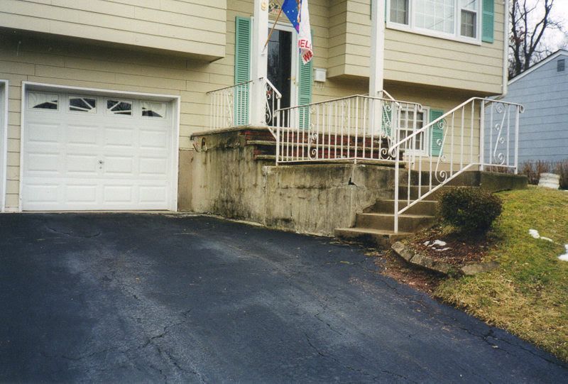 House exterior with garage, sloped driveway, and concrete steps with white railing