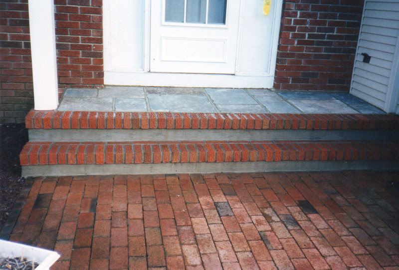 Brick front steps leading to a white door with a small porch and brick walkway
