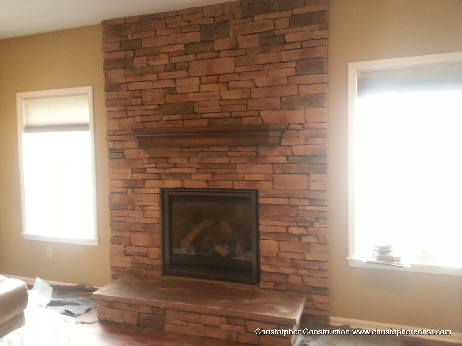 Living room fireplace with red brick surround, mantle, and two windows on either side