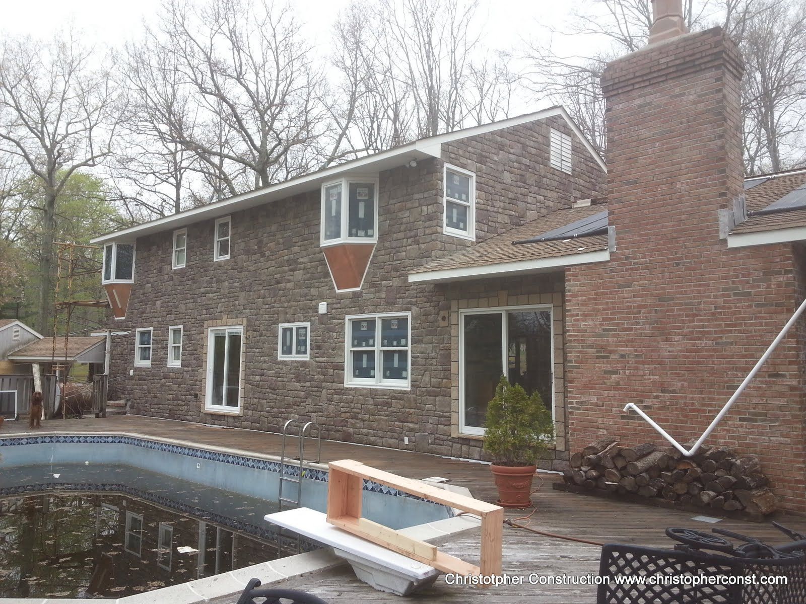 Brick house with a pool in the backyard and a deck beside large windows