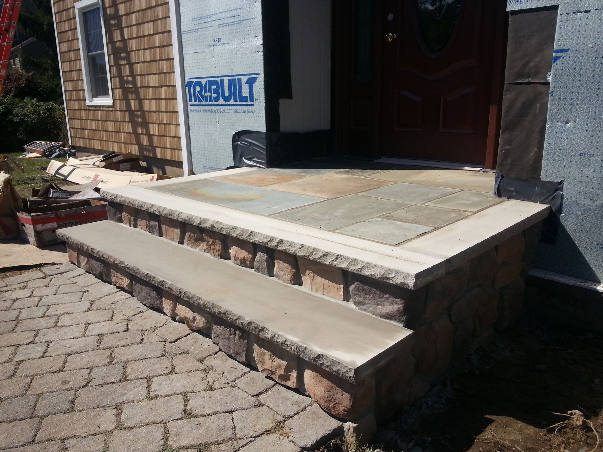Brick front steps and ramp leading to a doorway with a sign on the wall.