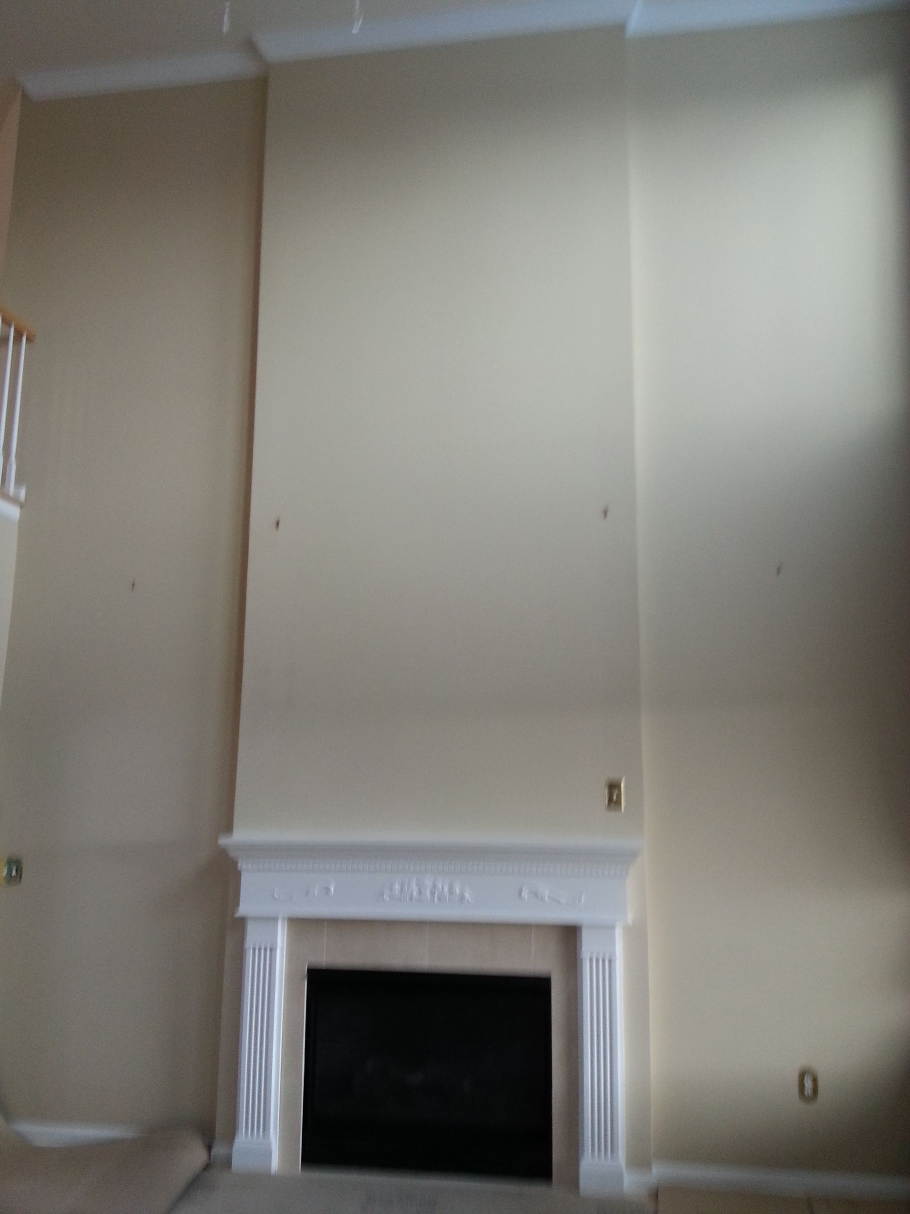 Empty beige living room wall with a white fireplace mantel and dark firebox.