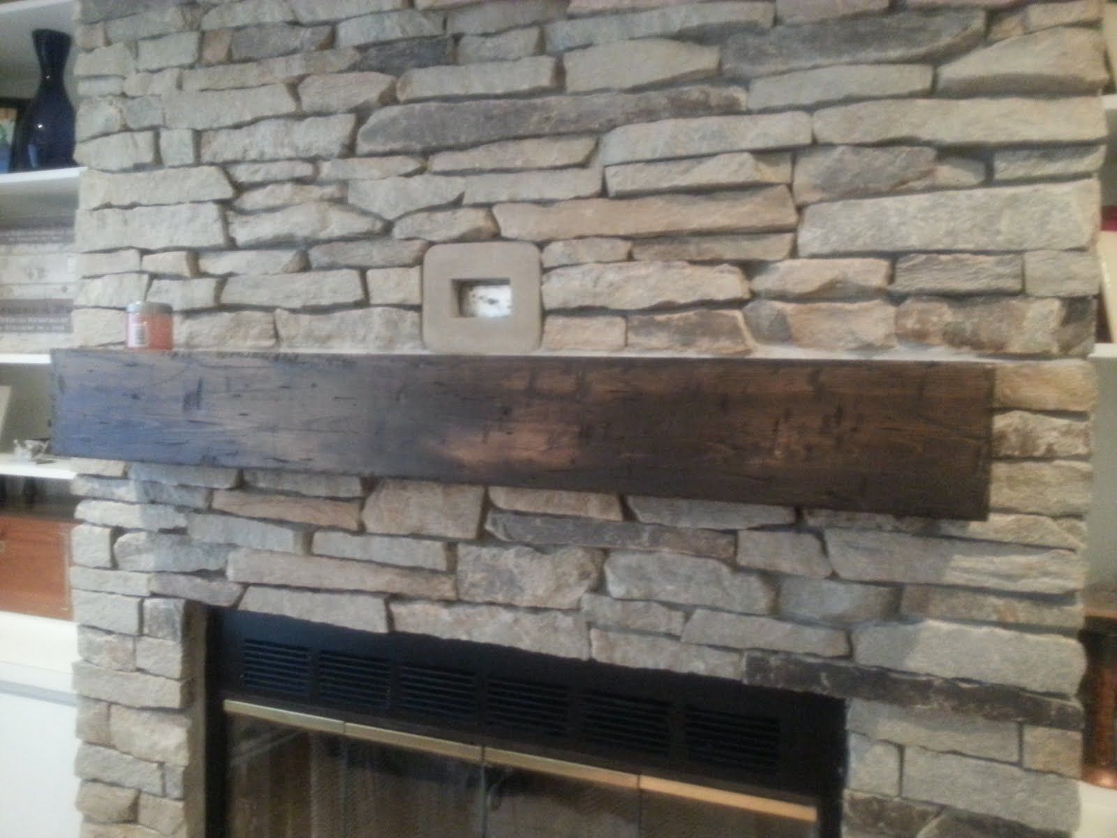 Stone fireplace with a dark wooden mantel and rectangular firebox opening in a rustic room