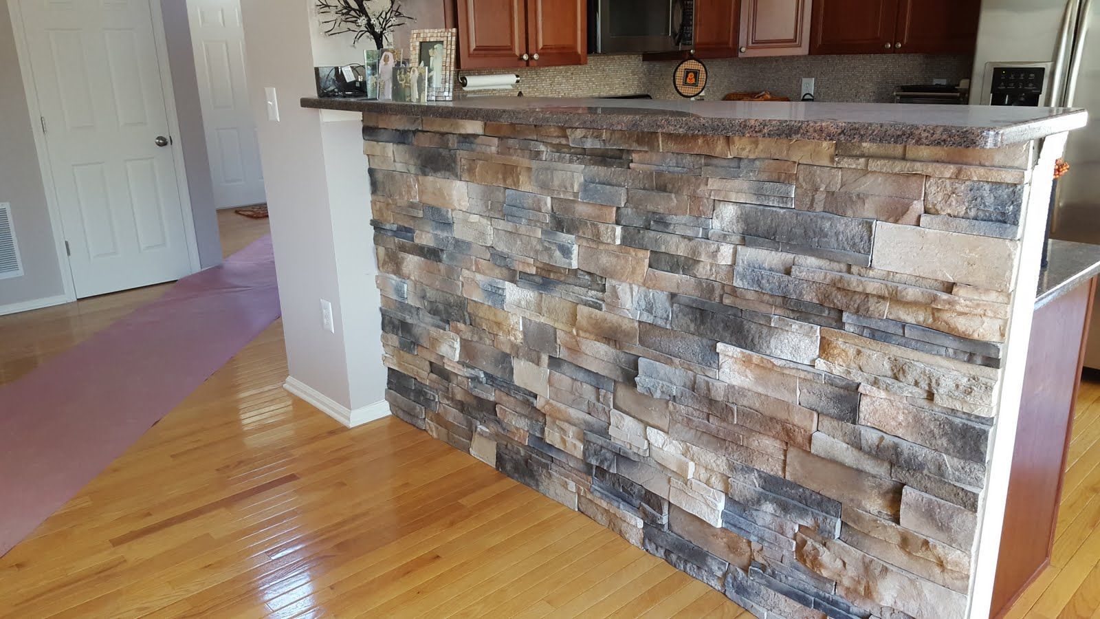 Kitchen with stone-faced breakfast bar, white countertop, and hardwood floor