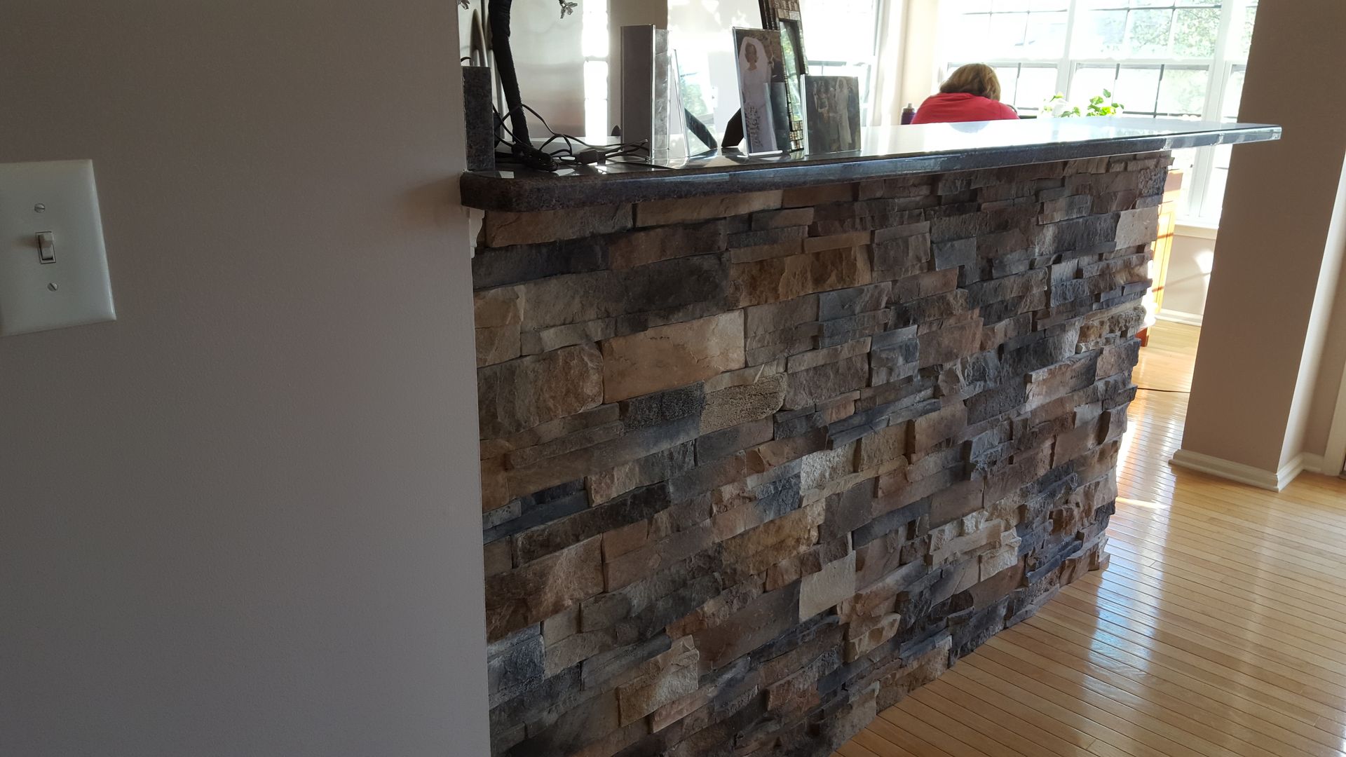 Stone-faced kitchen island with dark countertop in a bright home interior