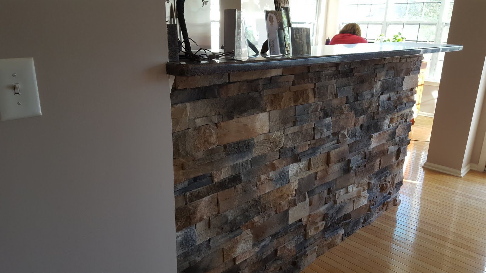 Stone-fronted indoor bar counter beside a bright window on a hardwood floor