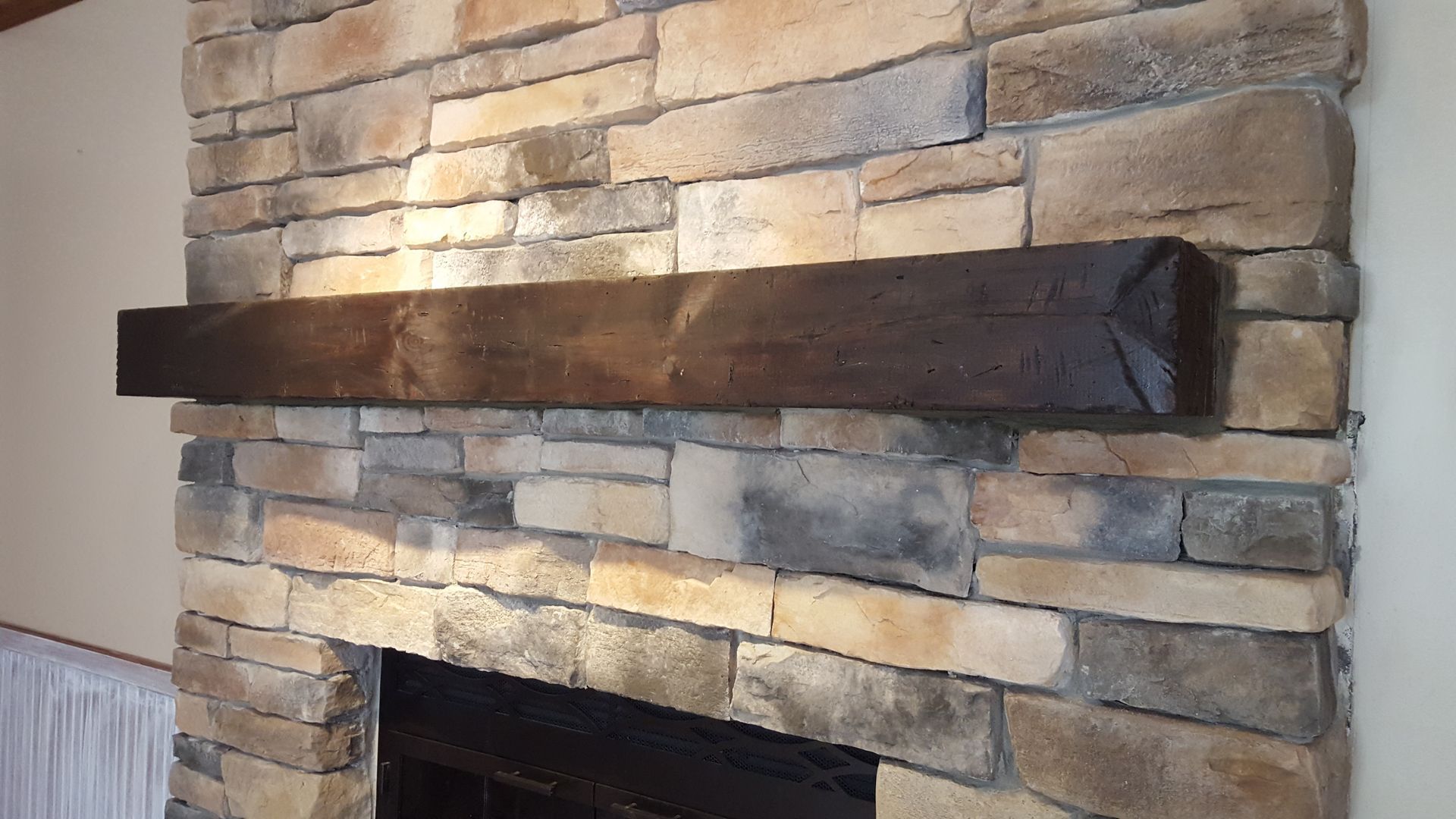 Stone fireplace with a dark wooden mantel shelf