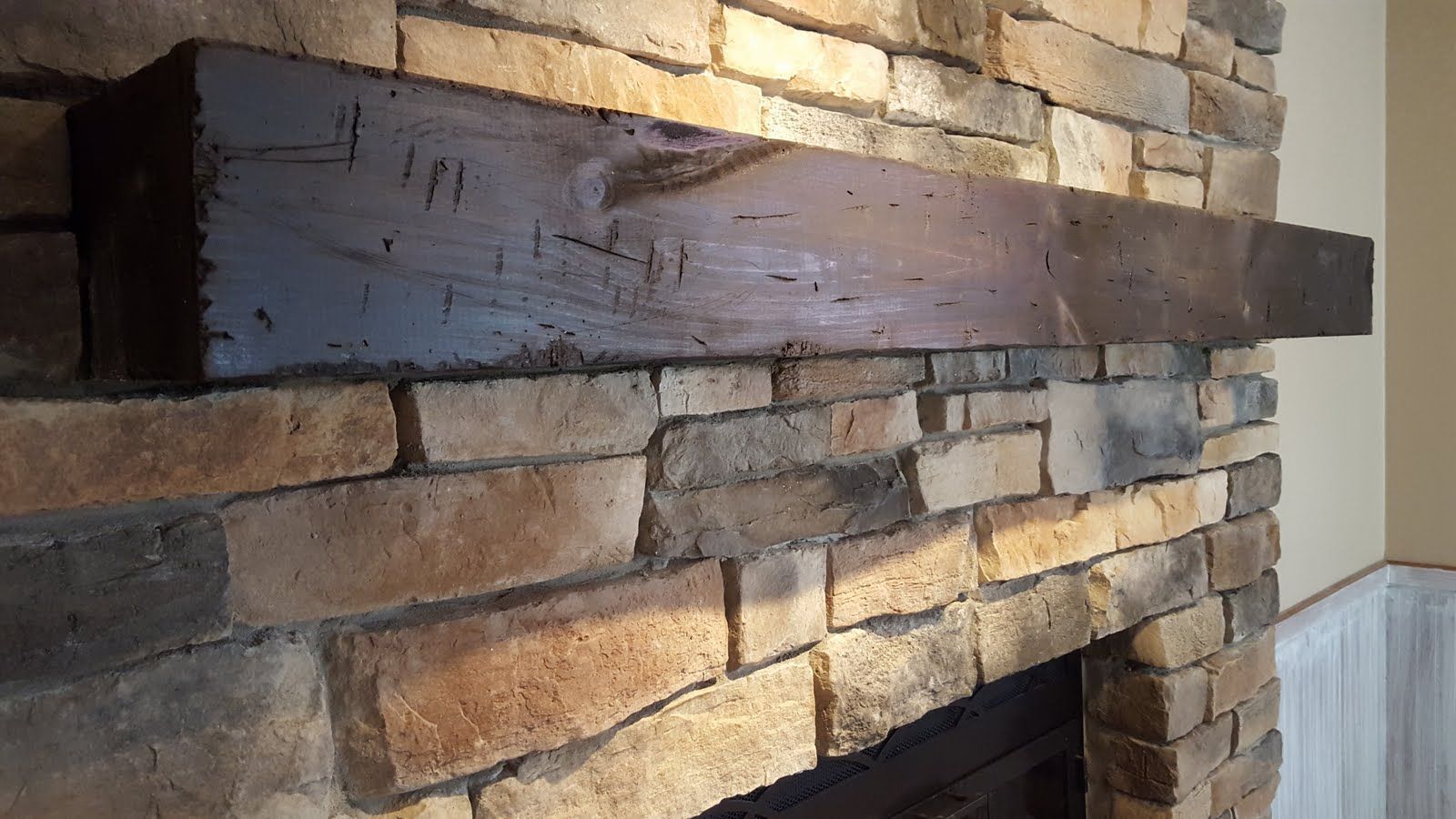 Rustic stone fireplace with a dark wooden mantel shelf indoors