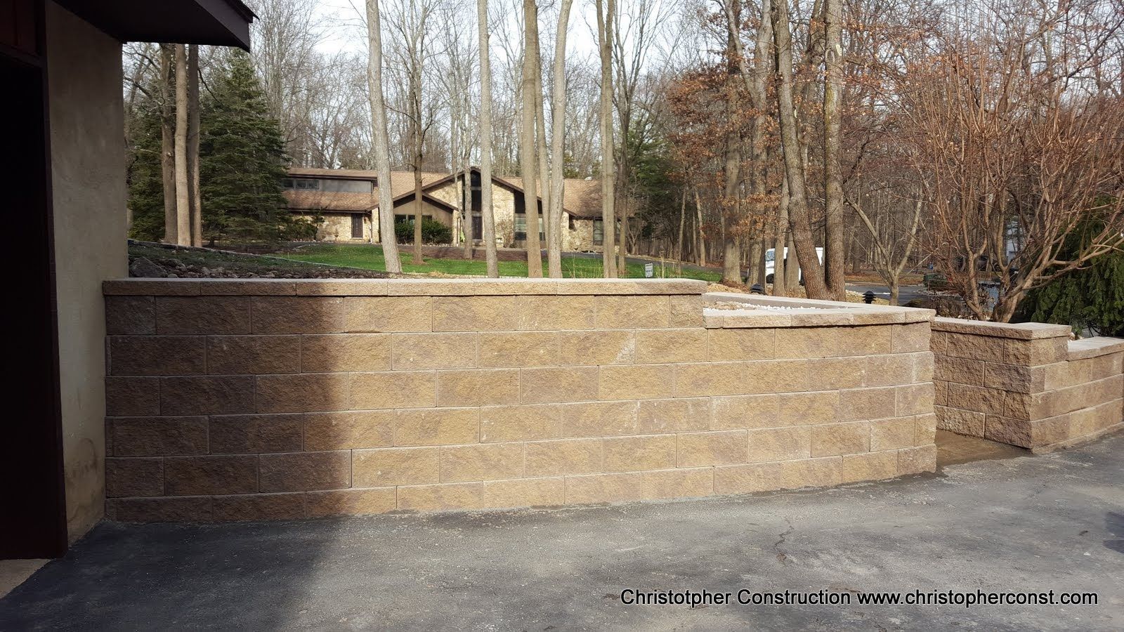 Brick retaining walls and steps in a park with leafless trees and a picnic table in the background