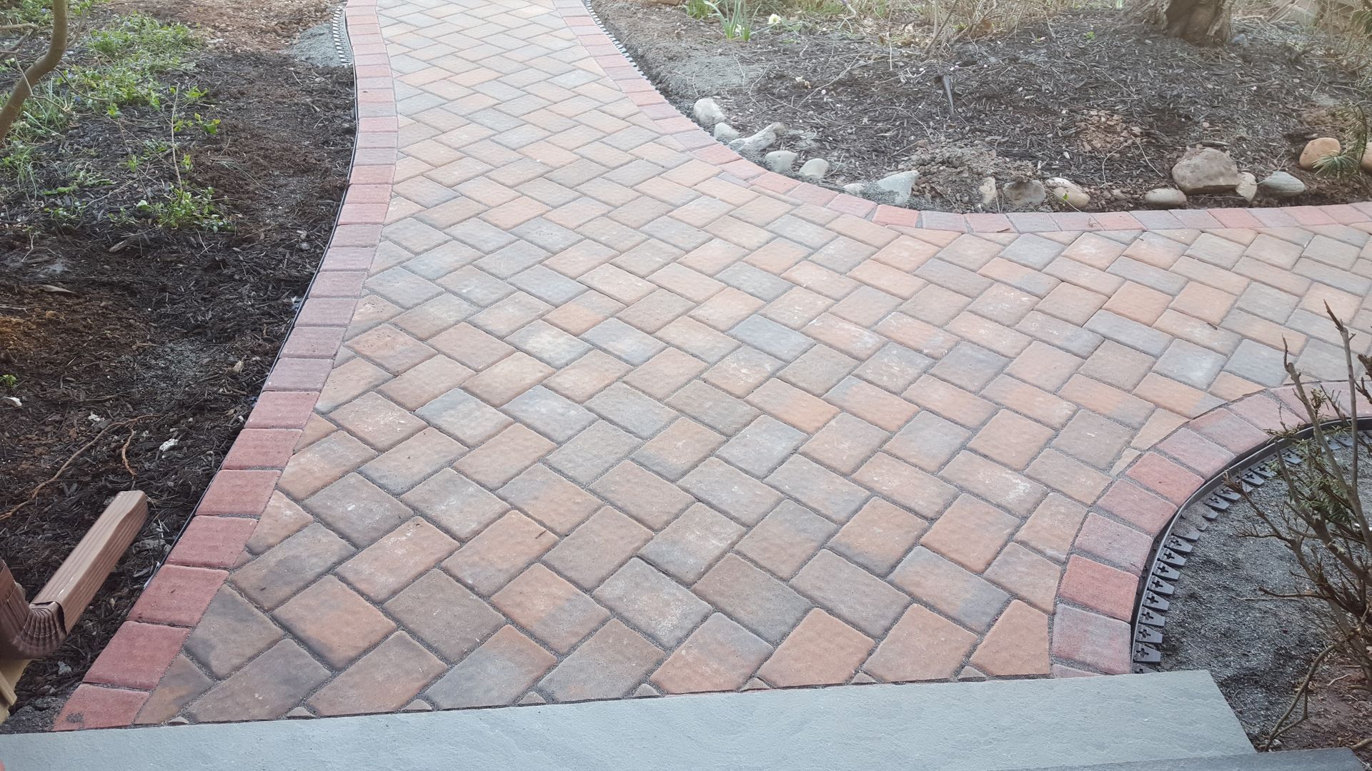 Brick garden walkway with curved borders and a step at the bottom