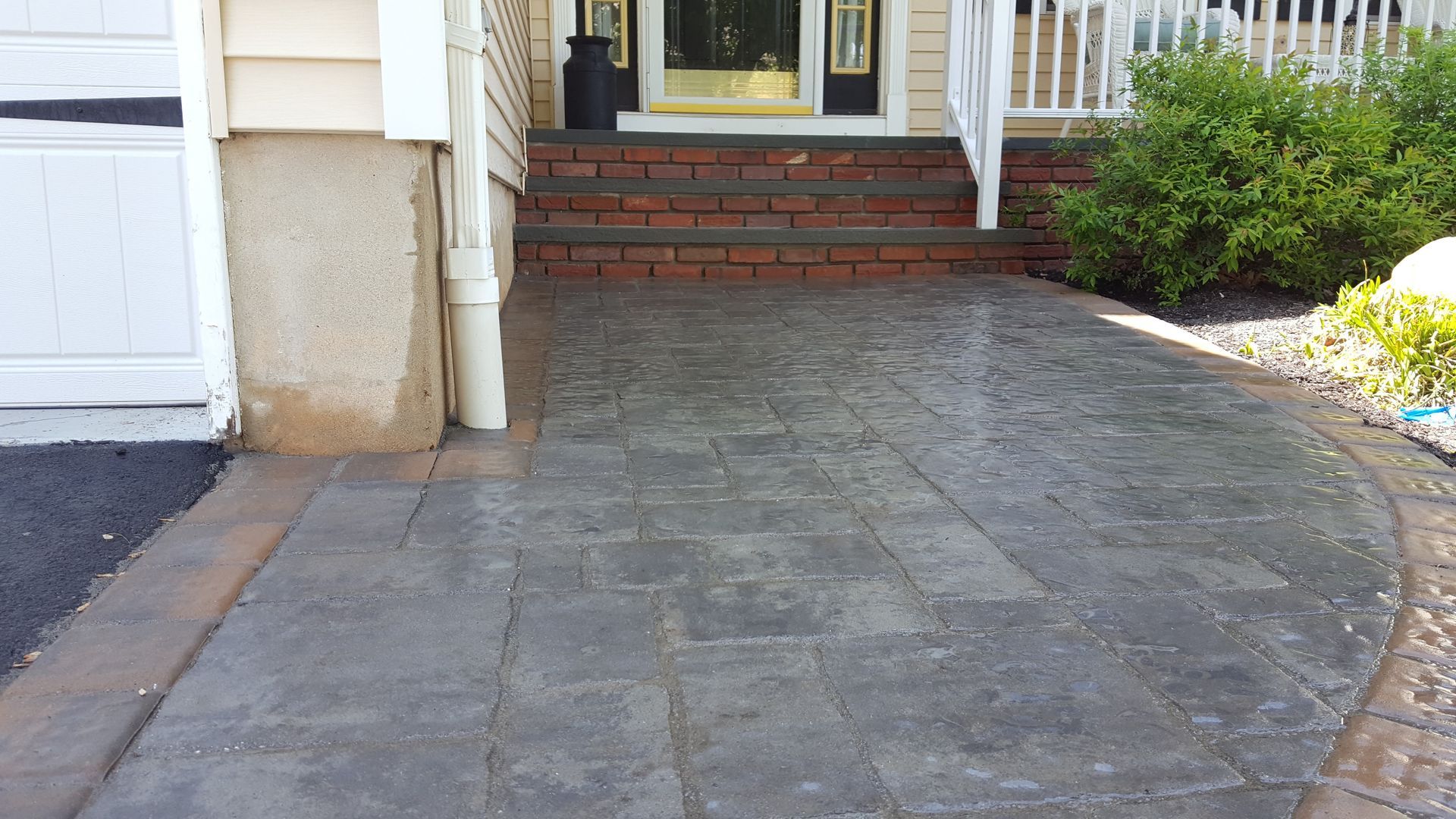 Curved stone driveway leading to brick front steps and a white house entrance