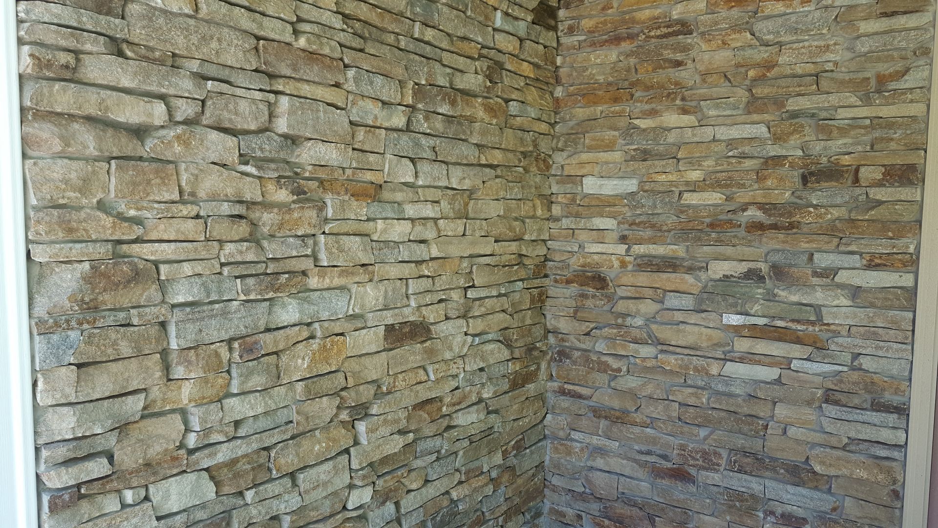 Corner of a room with stacked stone walls in tan, gray, and brown tones.