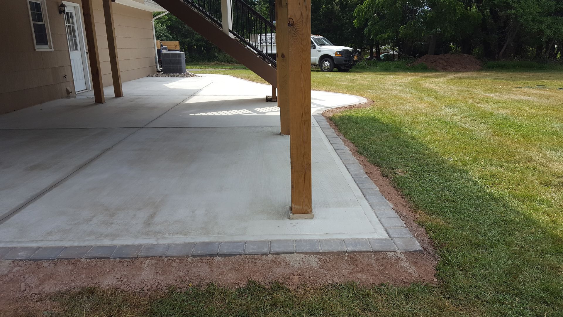 Concrete patio beside a lawn, with a wooden post supporting a covered porch.
