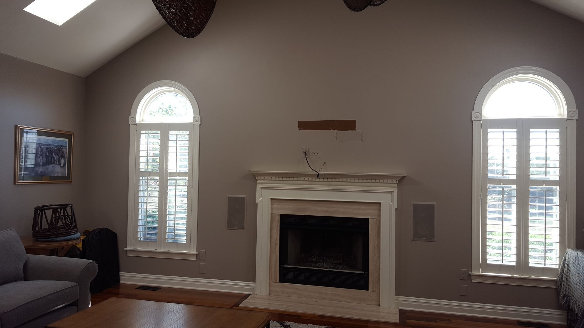 Living room with white fireplace centered between two arched windows and gray walls
