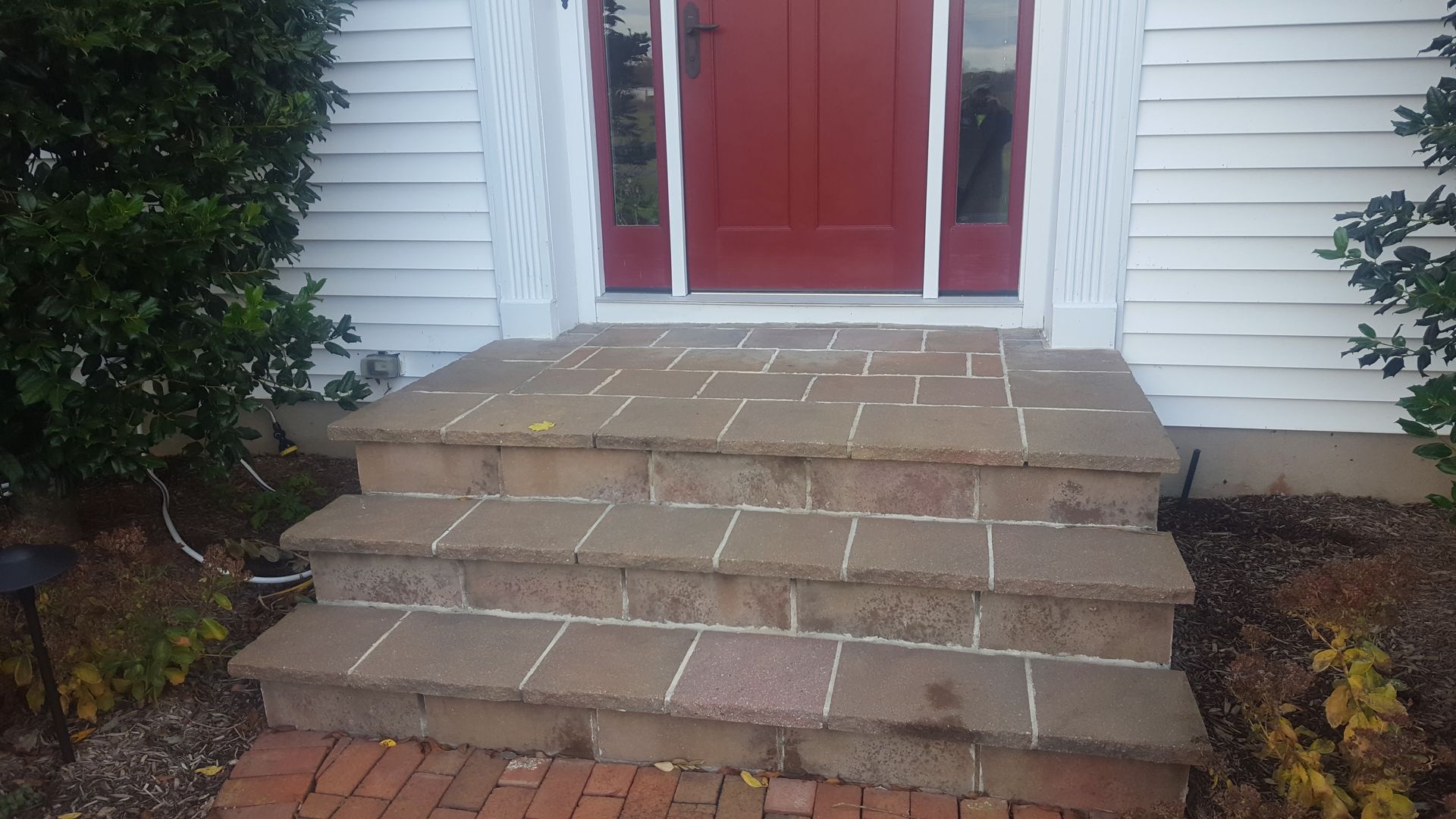 Brick steps leading to a red front door on a white house