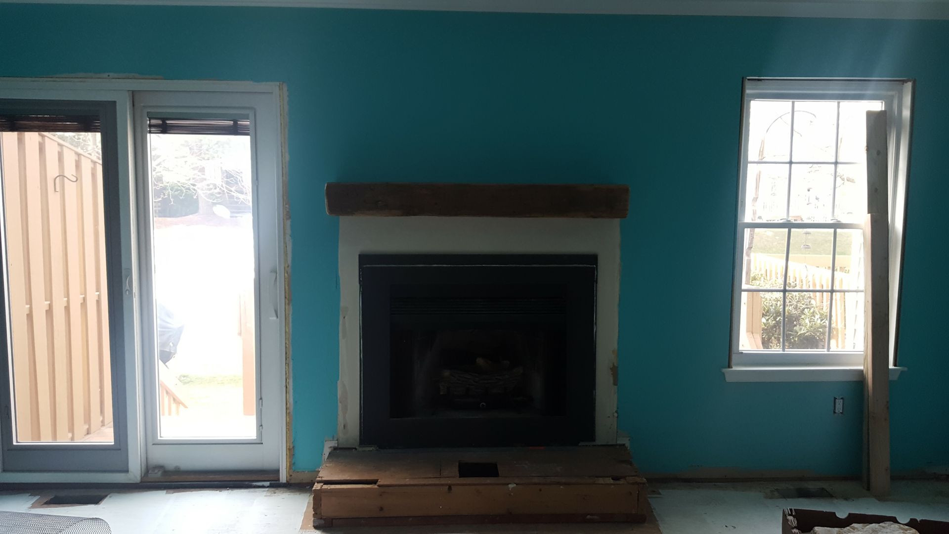 Teal living room wall with fireplace centered between a glass door and a window, bright daylight outside