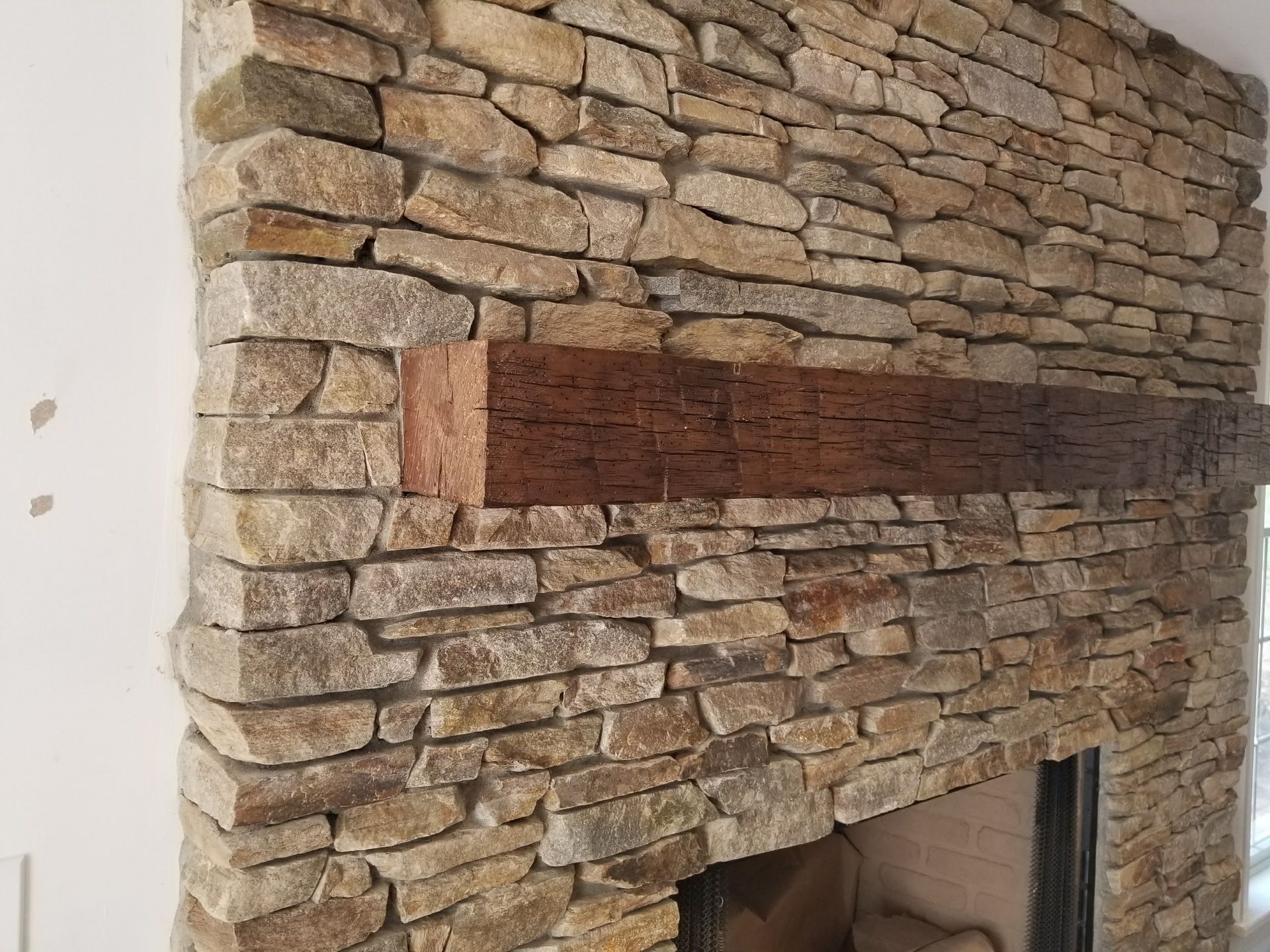 Stone fireplace with a wide horizontal red brick accent above the firebox opening