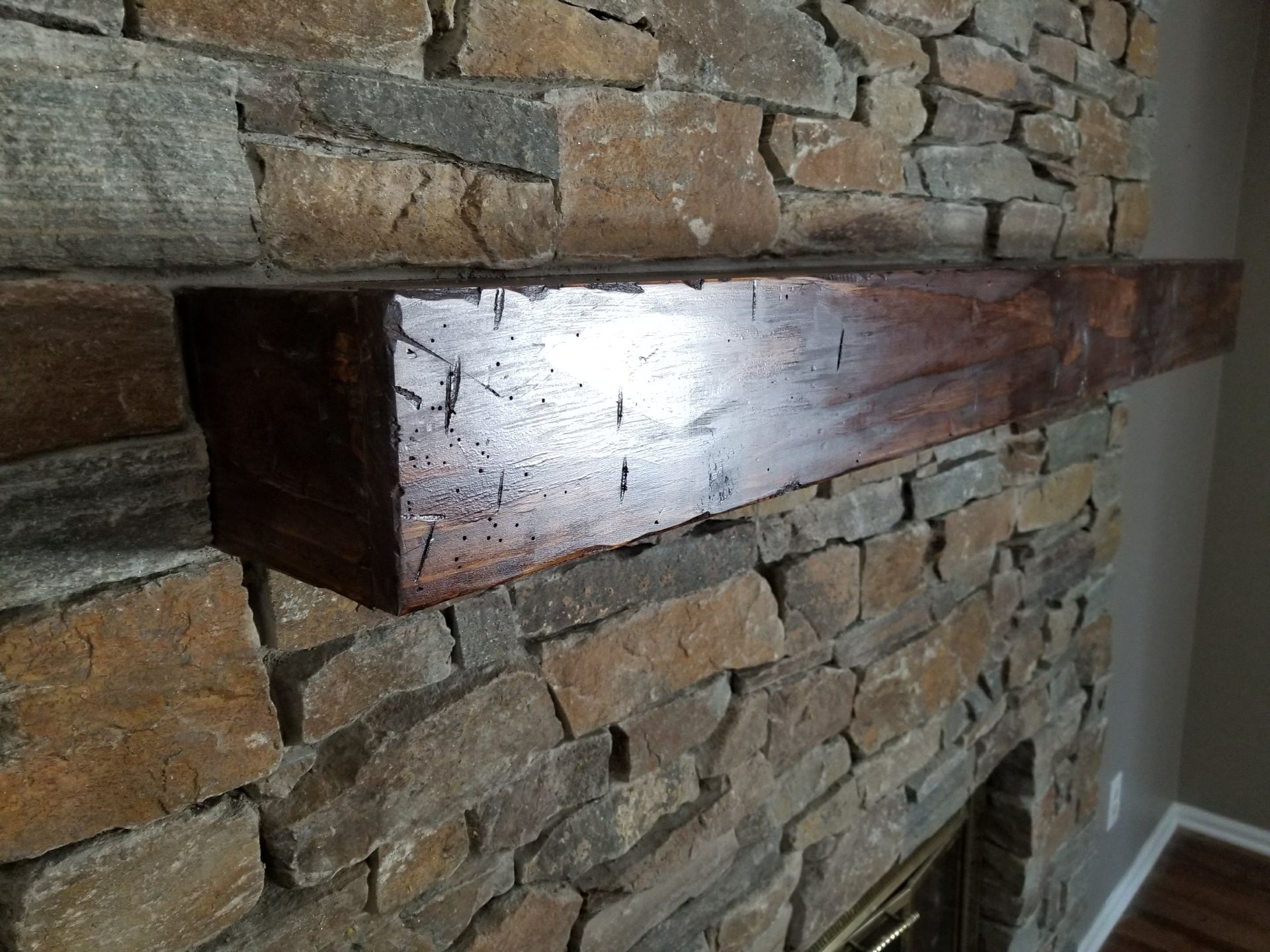 Wooden mantel shelf mounted on a stone fireplace wall