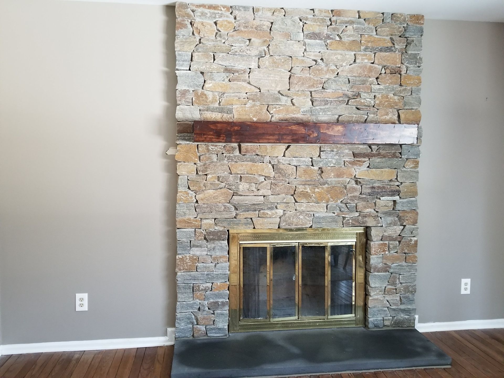 Stone fireplace with brass screen in a beige living room wall