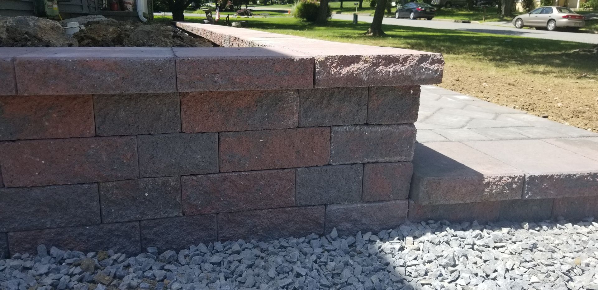 Brick retaining wall with steps and gravel in a sunny yard