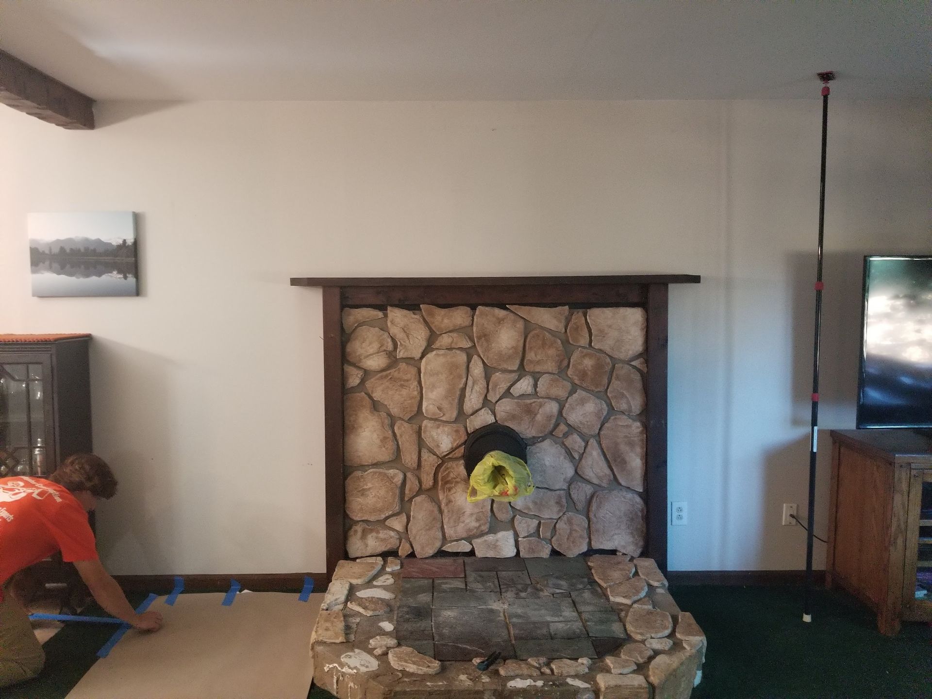Living room with stone fireplace, TV on right, and a person crouching at left.