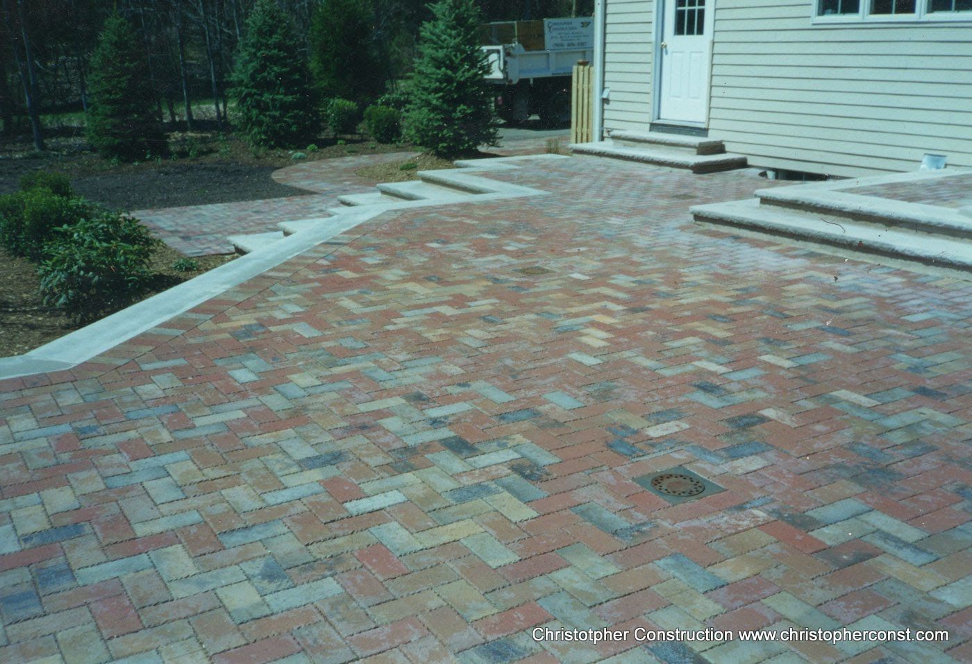 Brick patio beside a house with steps and a small garden path nearby