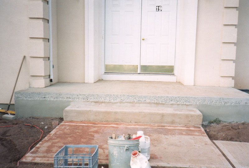 Front entrance with steps, unfinished walkway, and painting supplies in front of double doors