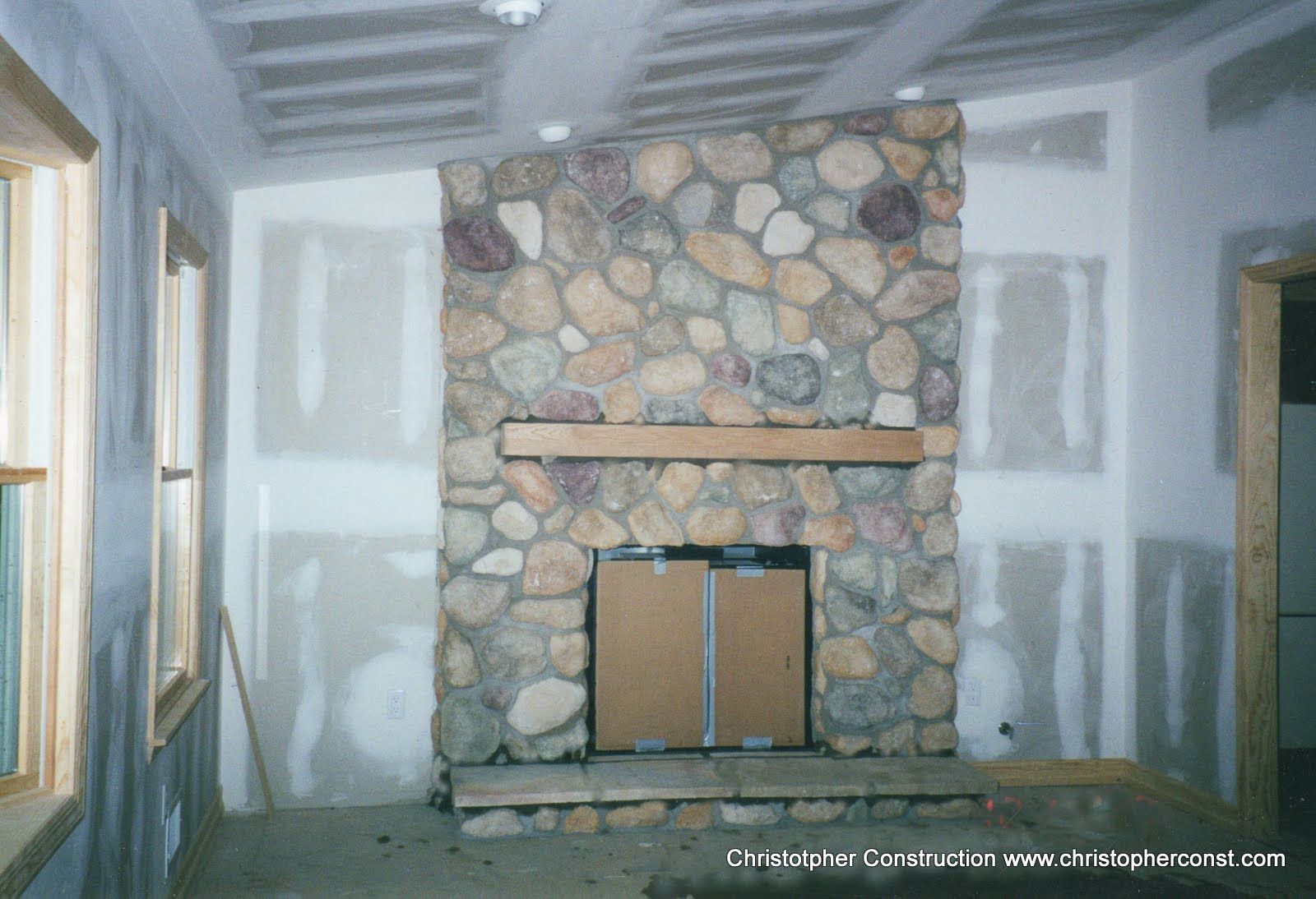 Stone fireplace with cardboard covering the opening in a room under renovation