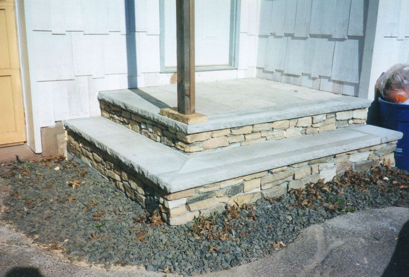 Stone porch steps with a wooden post beside a house exterior