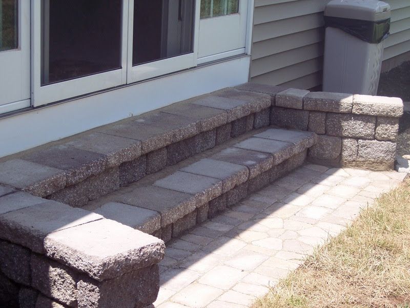 Front steps and short brick stairs leading to a house entrance with stone pillars and walkway