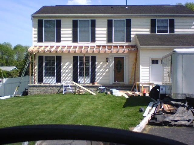 Two-story house with a striped awning over the patio and lawn in front.