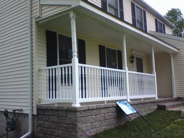 Front porch with white railings and stone steps on a house exterior