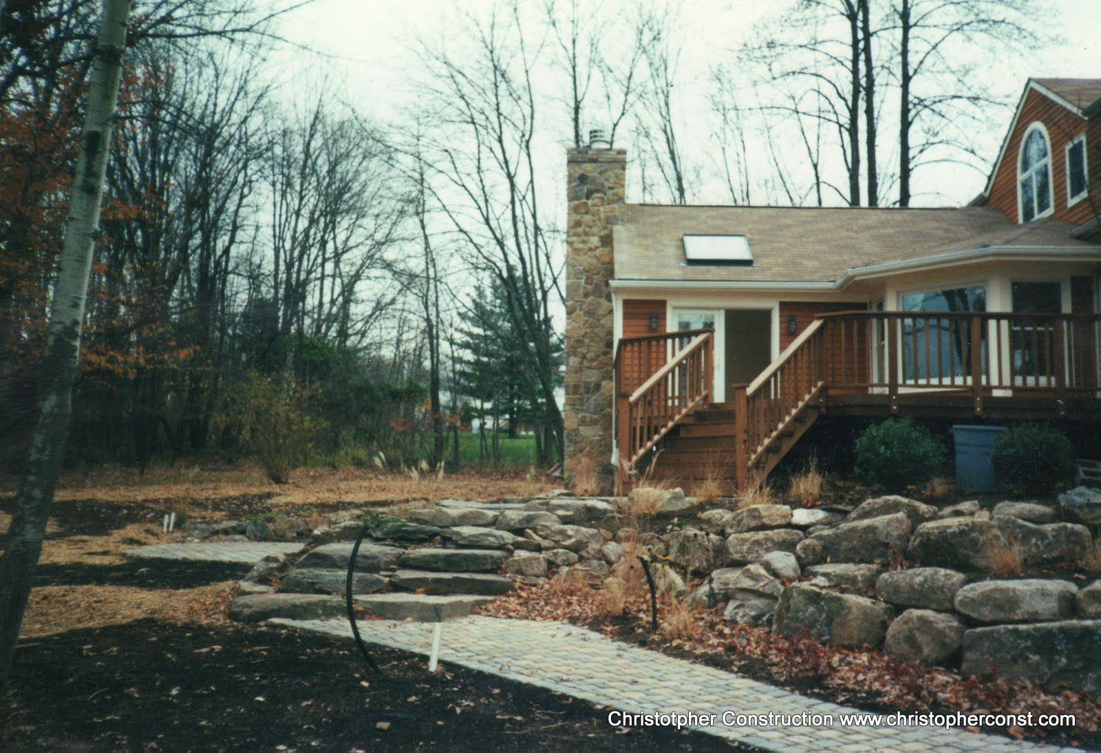 Wooden house with stone steps and leafless trees in a quiet wooded yard