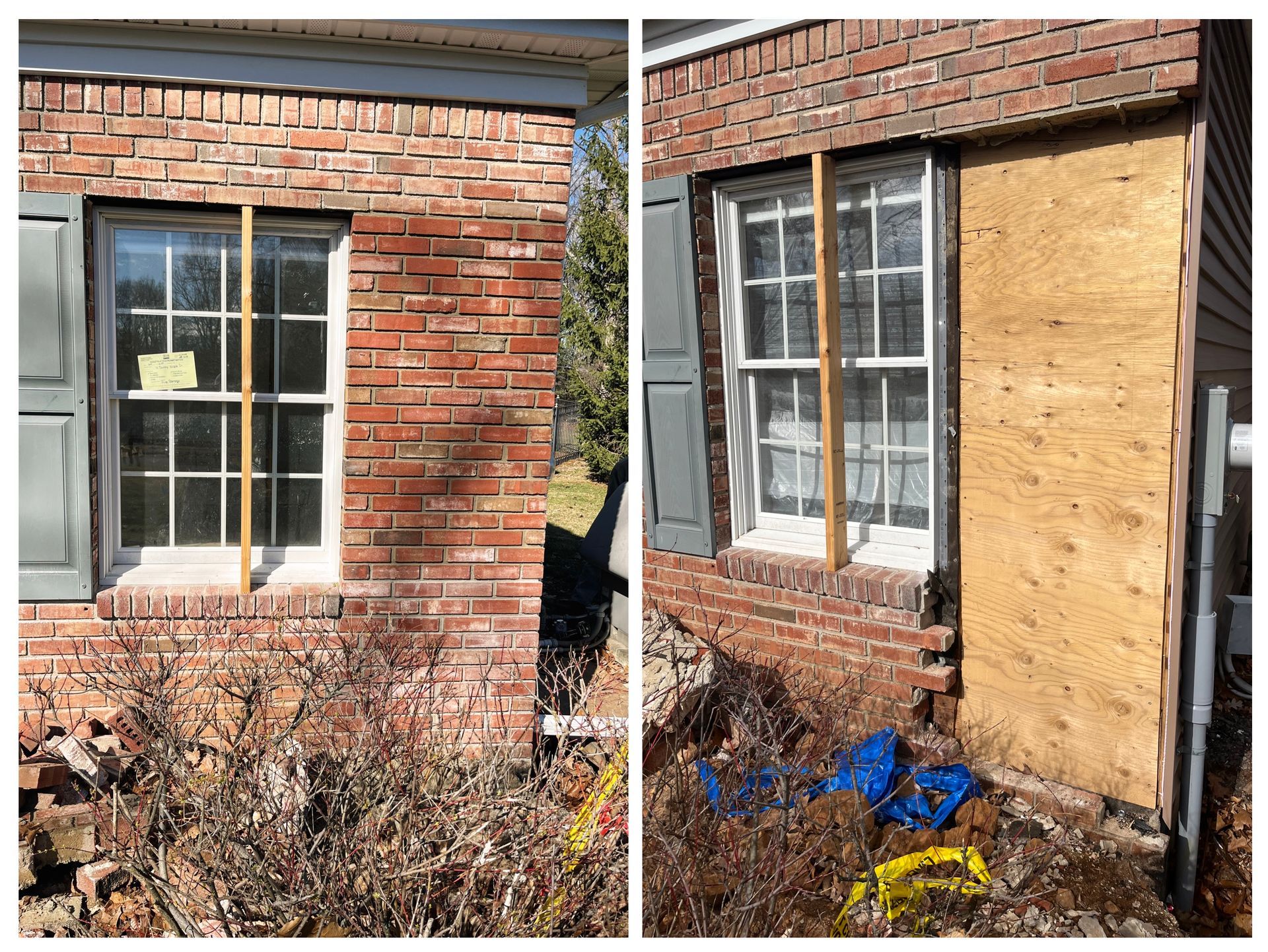 Two brick house windows, one boarded with plywood, with peeling paint and shrubs below