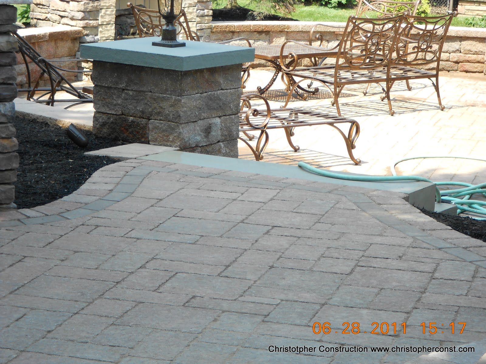 Stone patio with wicker chairs and a low stone fire pit in an outdoor seating area