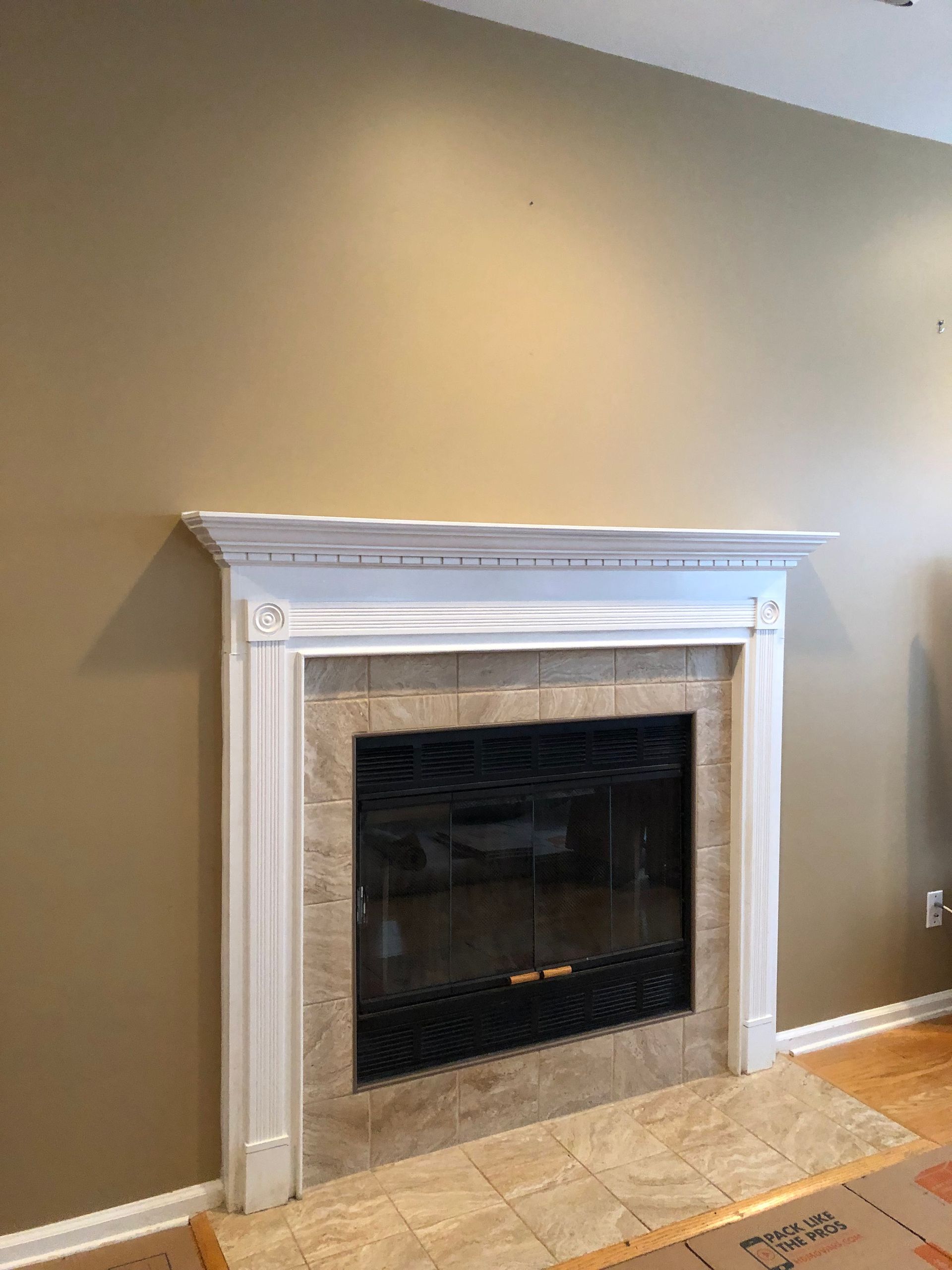 White fireplace with beige tile surround on a tan wall in a living room