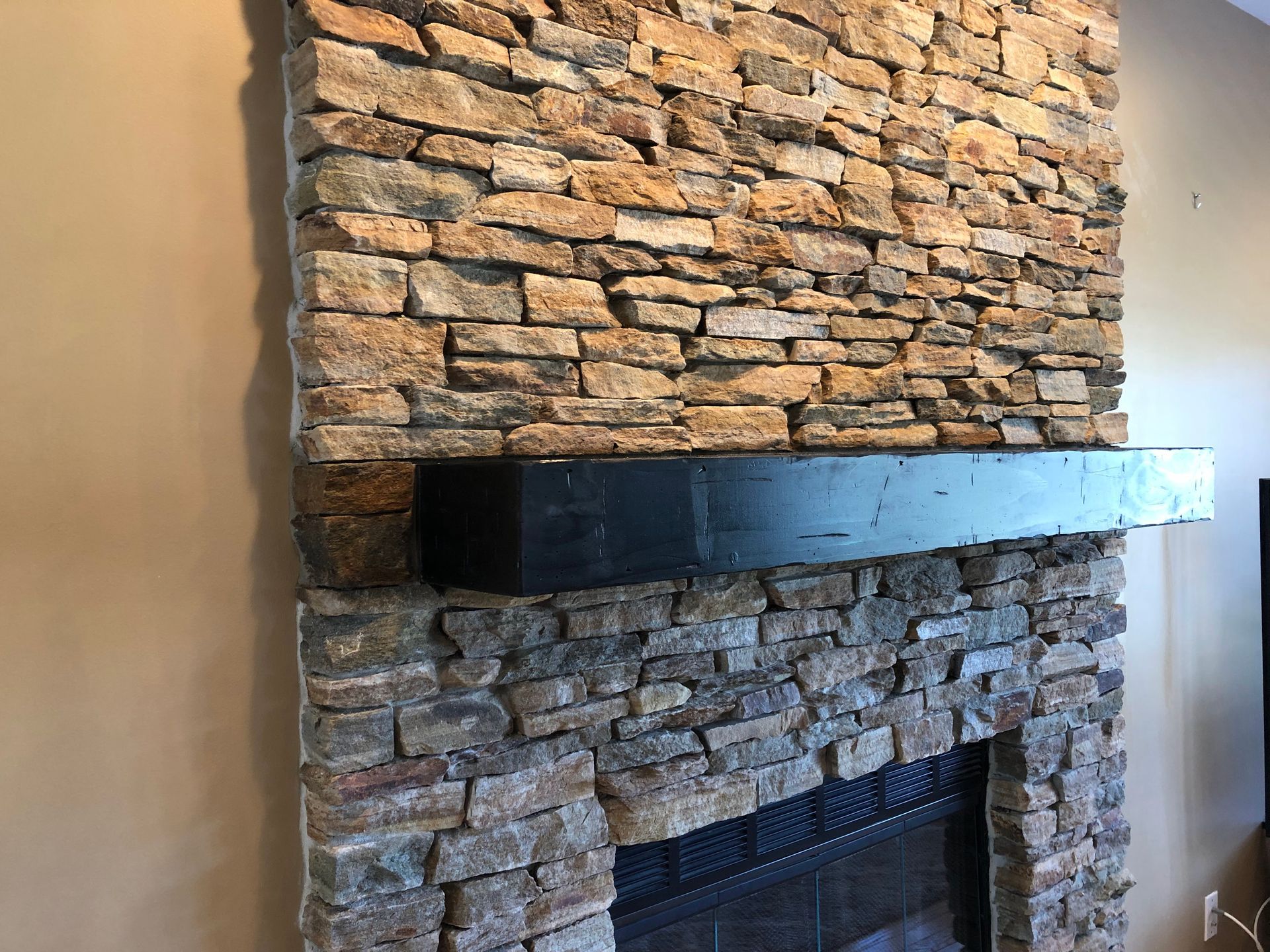 Stone fireplace with a dark mantel in a beige-walled room