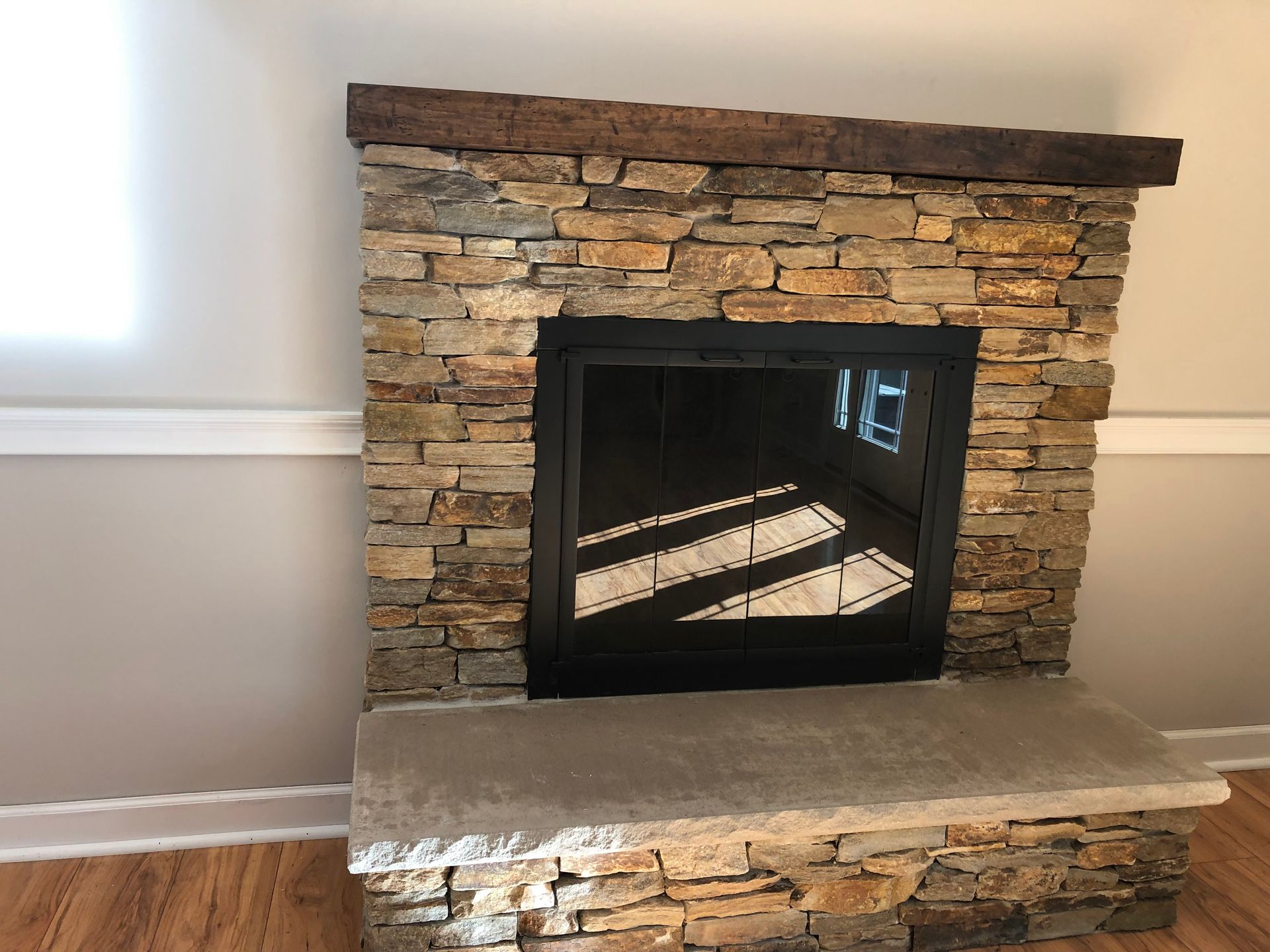 Stone fireplace with dark mantel and raised hearth in a bright room